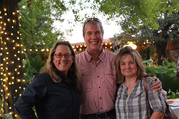 Rebecca Turner with guests at dusk in the gardens with lights on